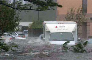 A flooded street with a truck and car in it.