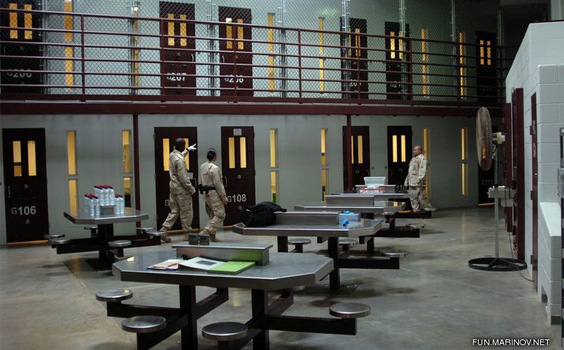 A prison cell with two men walking around.