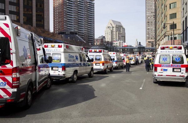 A line of ambulances are parked in the street.